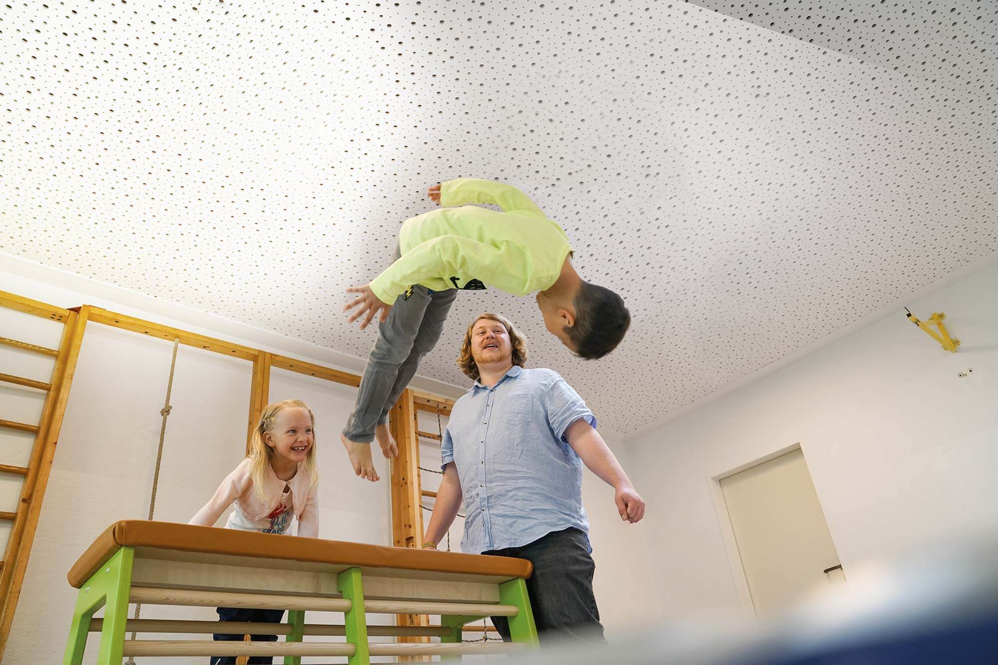 Sportlicher Spaß: Unsere Kindertagesstätte in Bewegung Der Kindergartenmitarbeiter und die Kinder haben sichtlich Spaß beim sportlichen Abenteuer, beim Springen vom Bock auf eine weiche Matte.