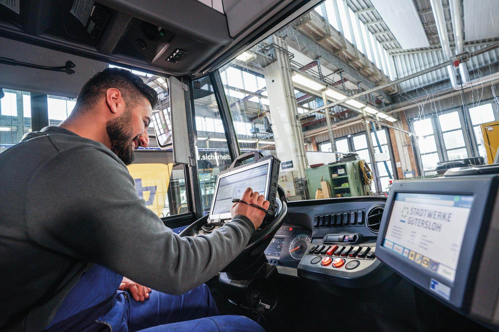 Die Technik im Griff: Unser Mechatroniker gewährleistet perfekte Softwarefunktionalität Der Busmechatroniker der Stadt Gütersloh arbeitet an der Bus-Technik und überprüft sorgfältig die Software, um sicherzustellen, dass alles reibungslos funktioniert.