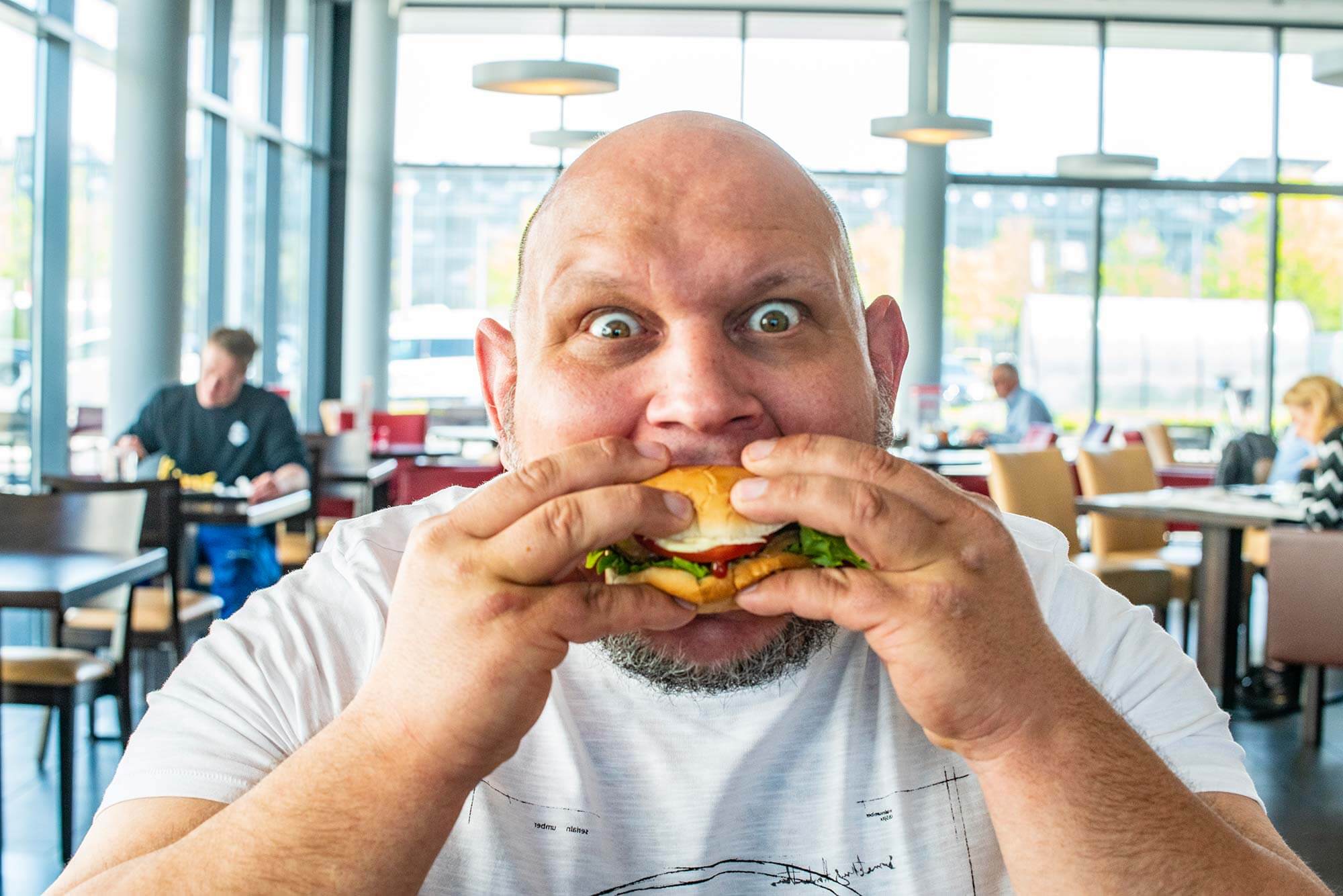 Frischer als Frisch zubereitet: Unser Mitarbeiter genießt den authentischen Tönnies-Burger Ein Mitarbeiter bei Tönnies genießt einen saftigen Burger, der direkt vor Ort hergestellt wird.